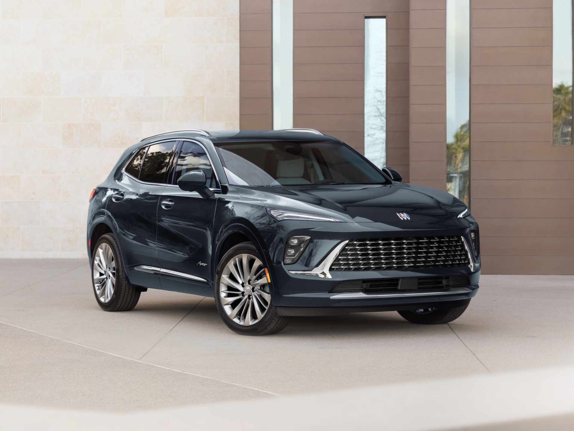 A Dark Blue Buick Envision SUV Parked Outside a Modern Building, Viewed from the Front Passenger Side