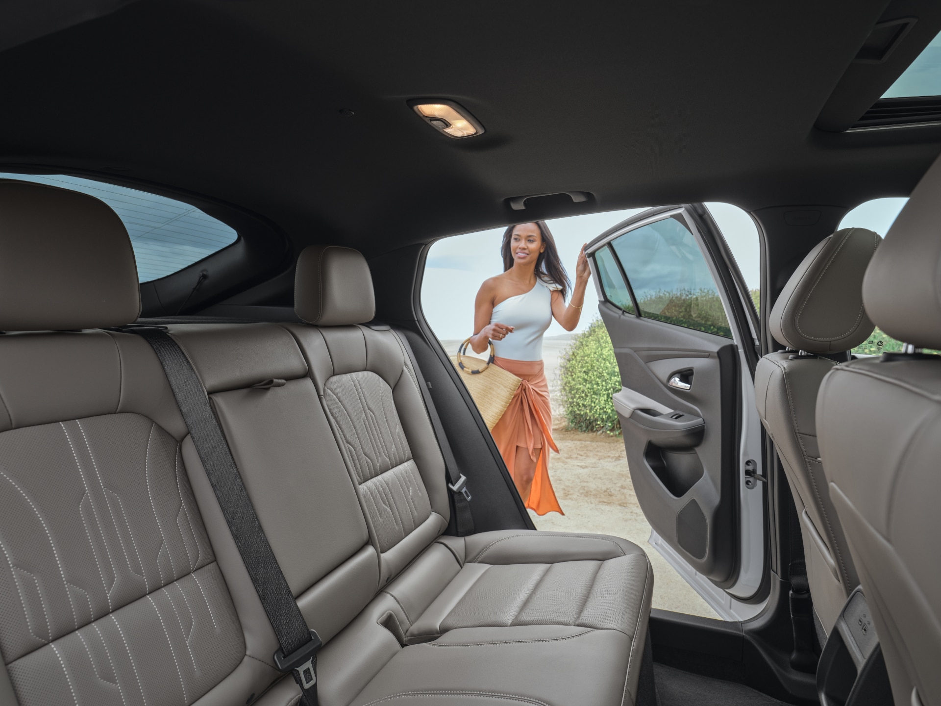 The Rear Passenger Seats of a Buick Envision, With a Person Opening the Car Door in a Bright Outdoor Setting