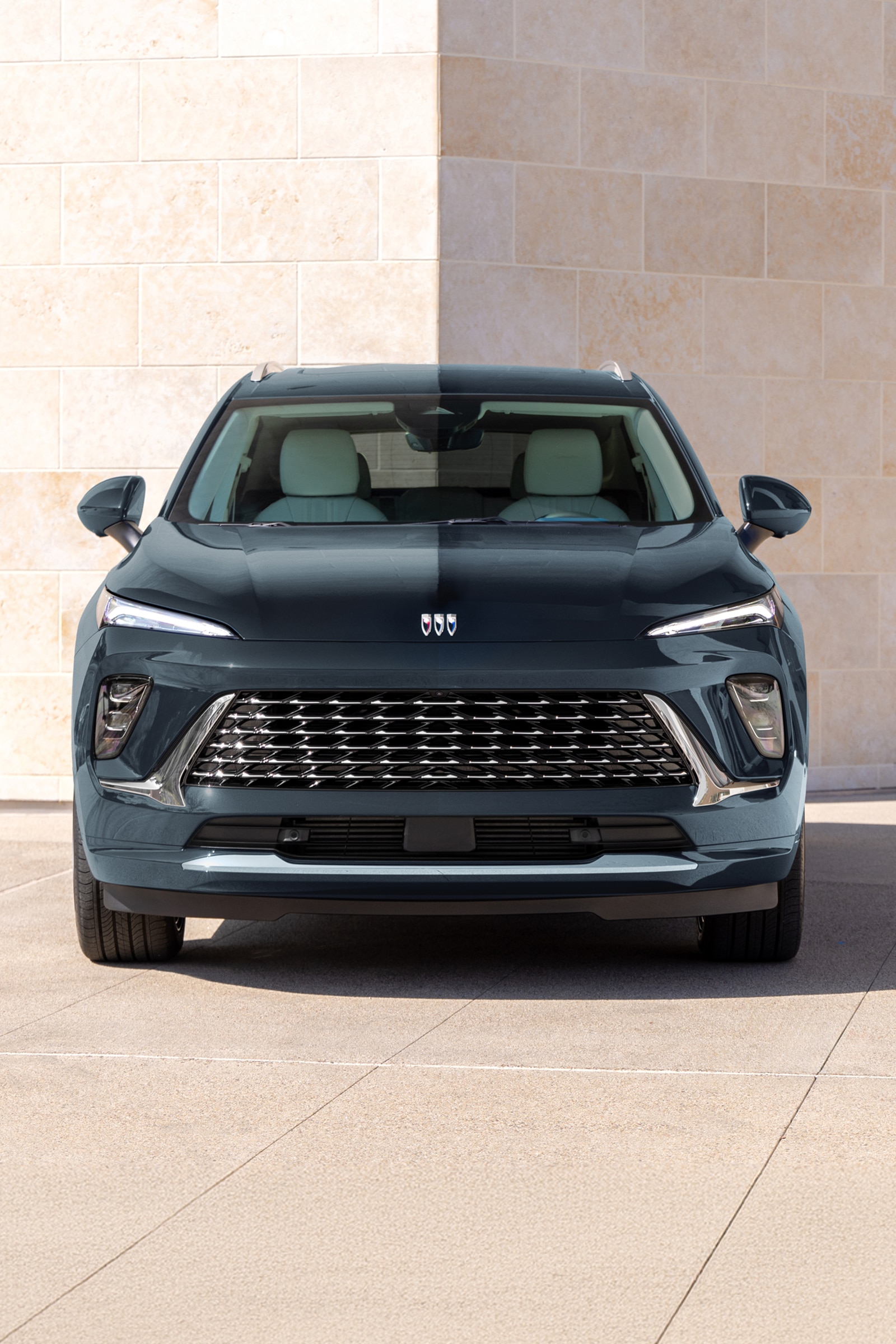 The Front of a Dark Blue Buick Envision SUV Parked Outside a Modern Building