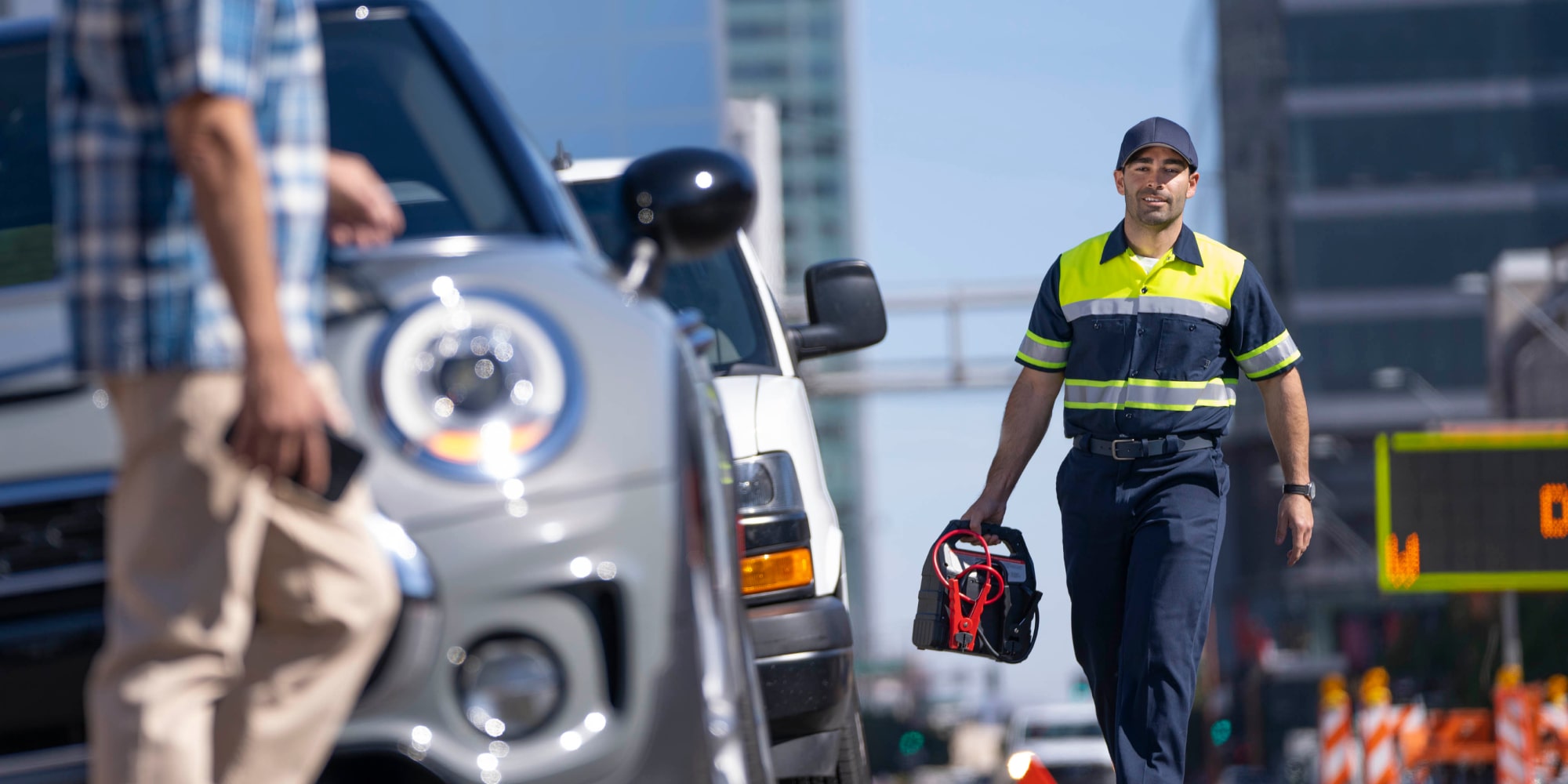 A Roadside Assistance Worker Walking Towards a Man and his Vehicle on the Side of the Road