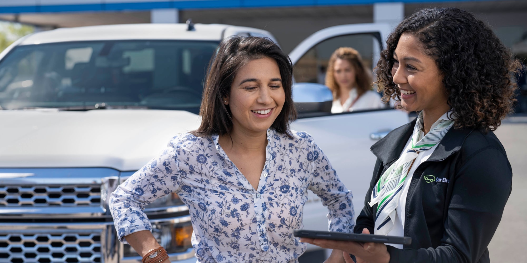 A CarBravo Certified Associate Helping a Woman Find a Used Car at a Dealership
