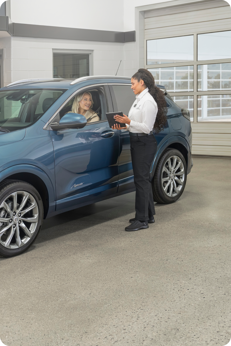 A Certified Service Technician Speaking to a Customer in Her Blue Buick SUV