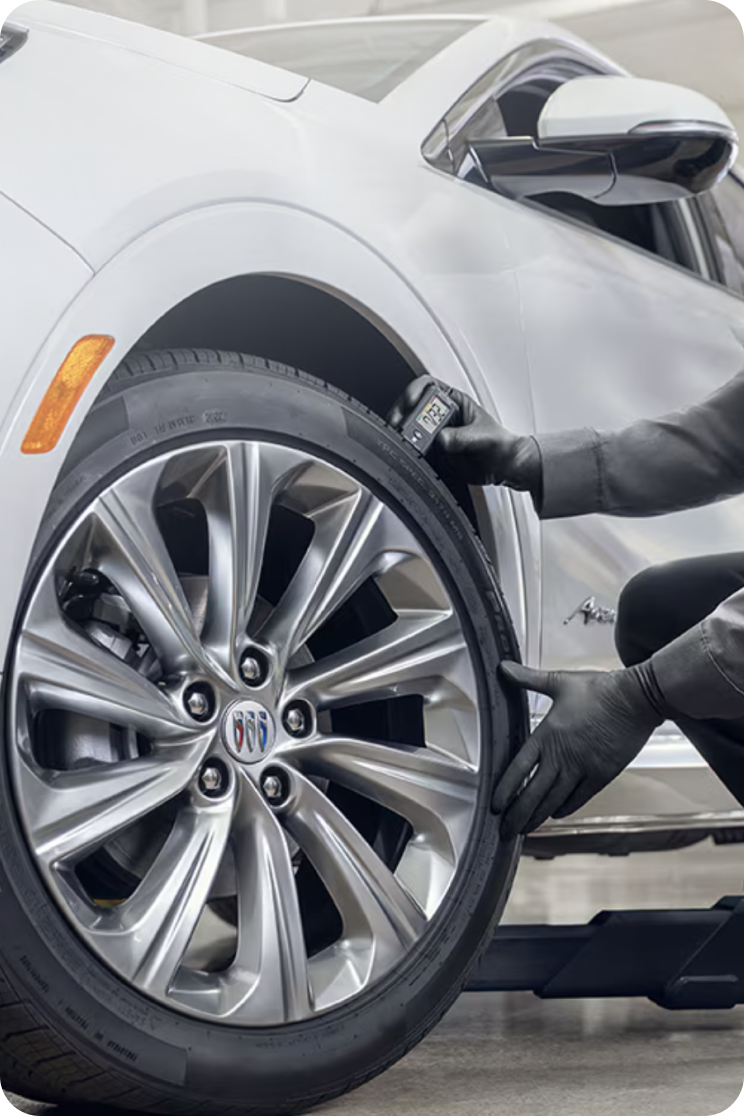 A Certified Service Technician Bending Down to Inspect a Tire