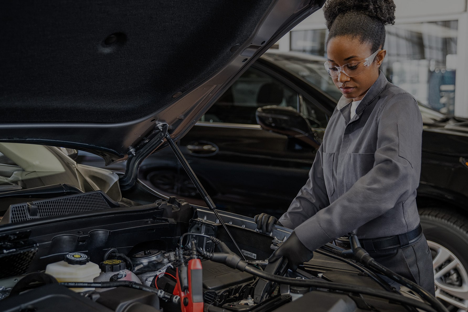A Female Service Technician Working on a Vehicle with a Lifted Hood