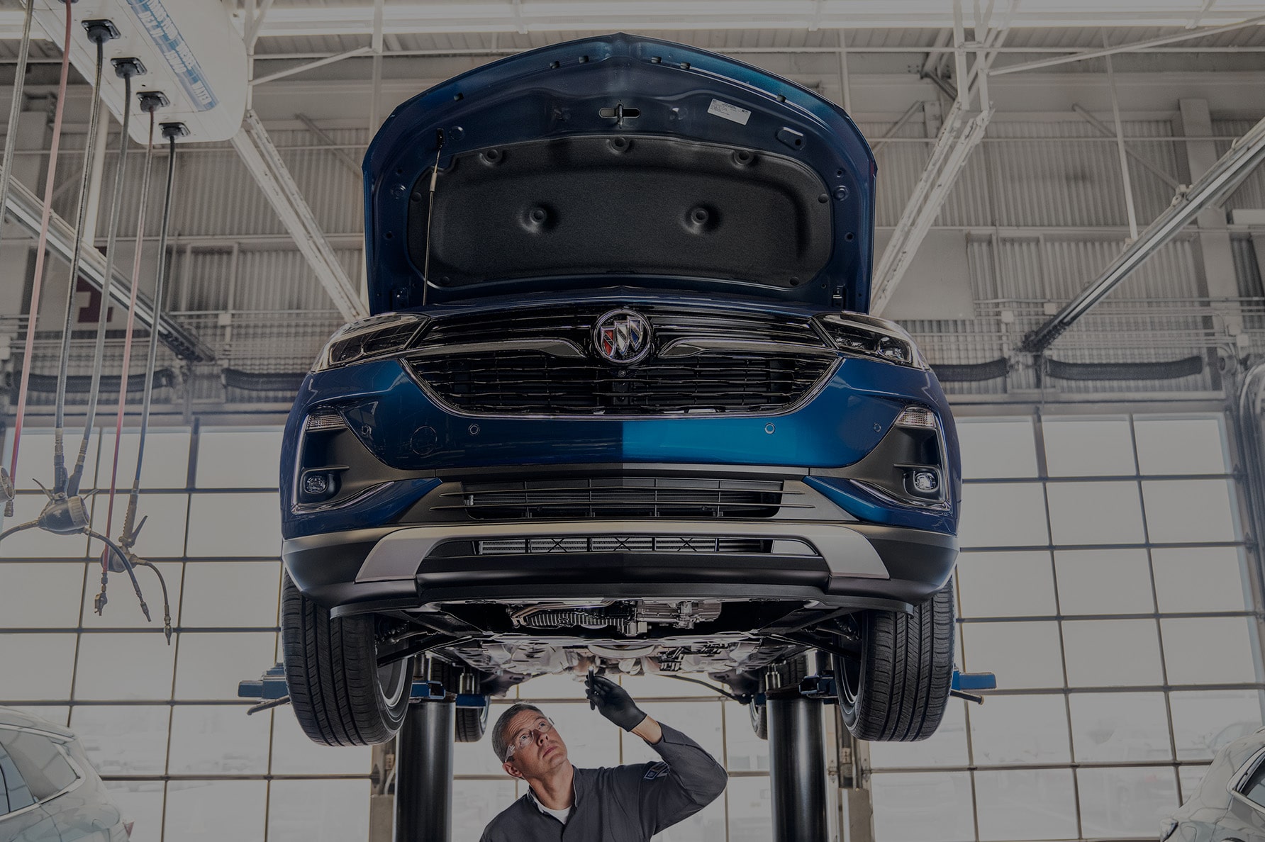 A Upwards View of a Lifted Vehicle with a Service Technician Underneath
