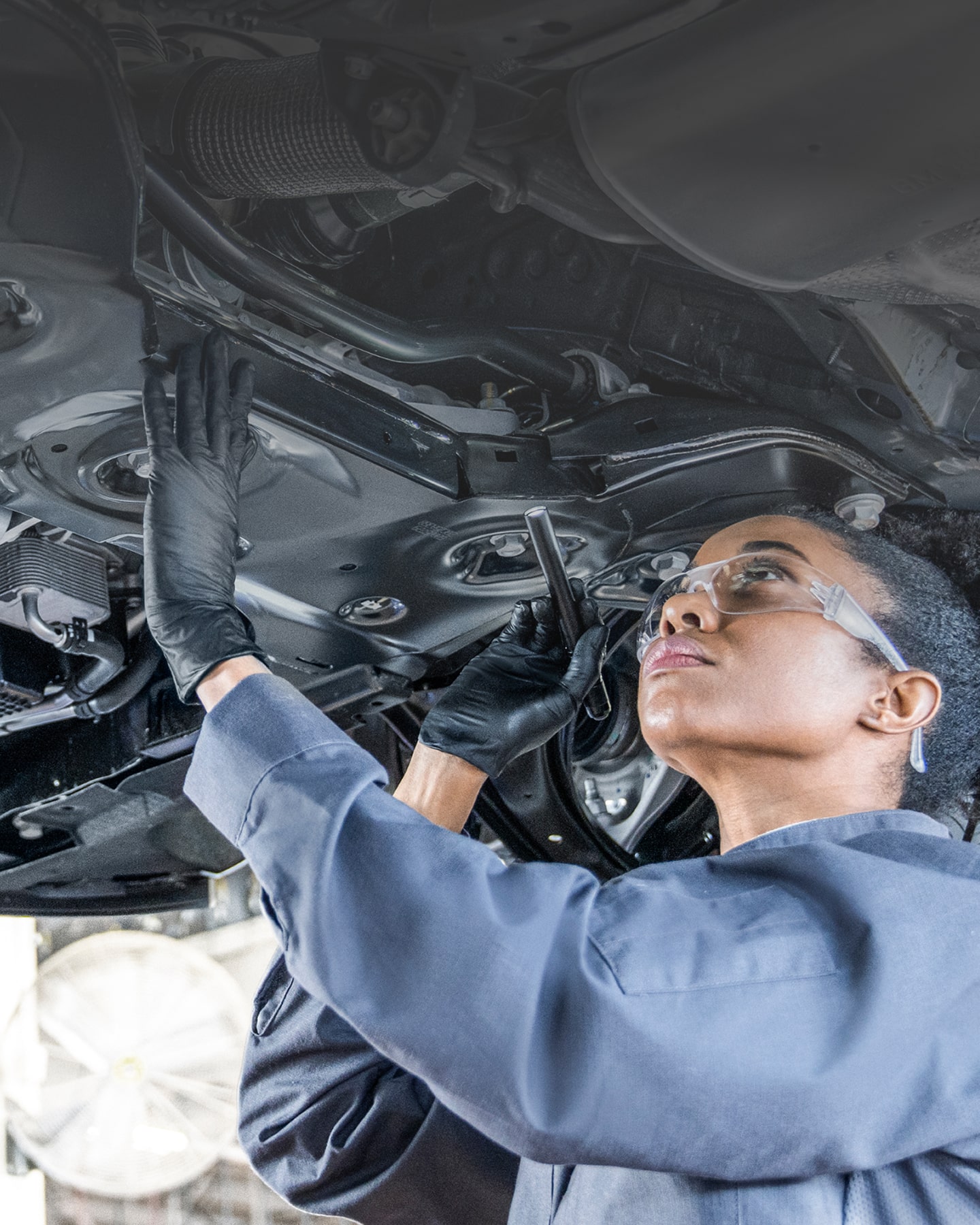 A Service Technician Working Underneath a Lifted Vehicle