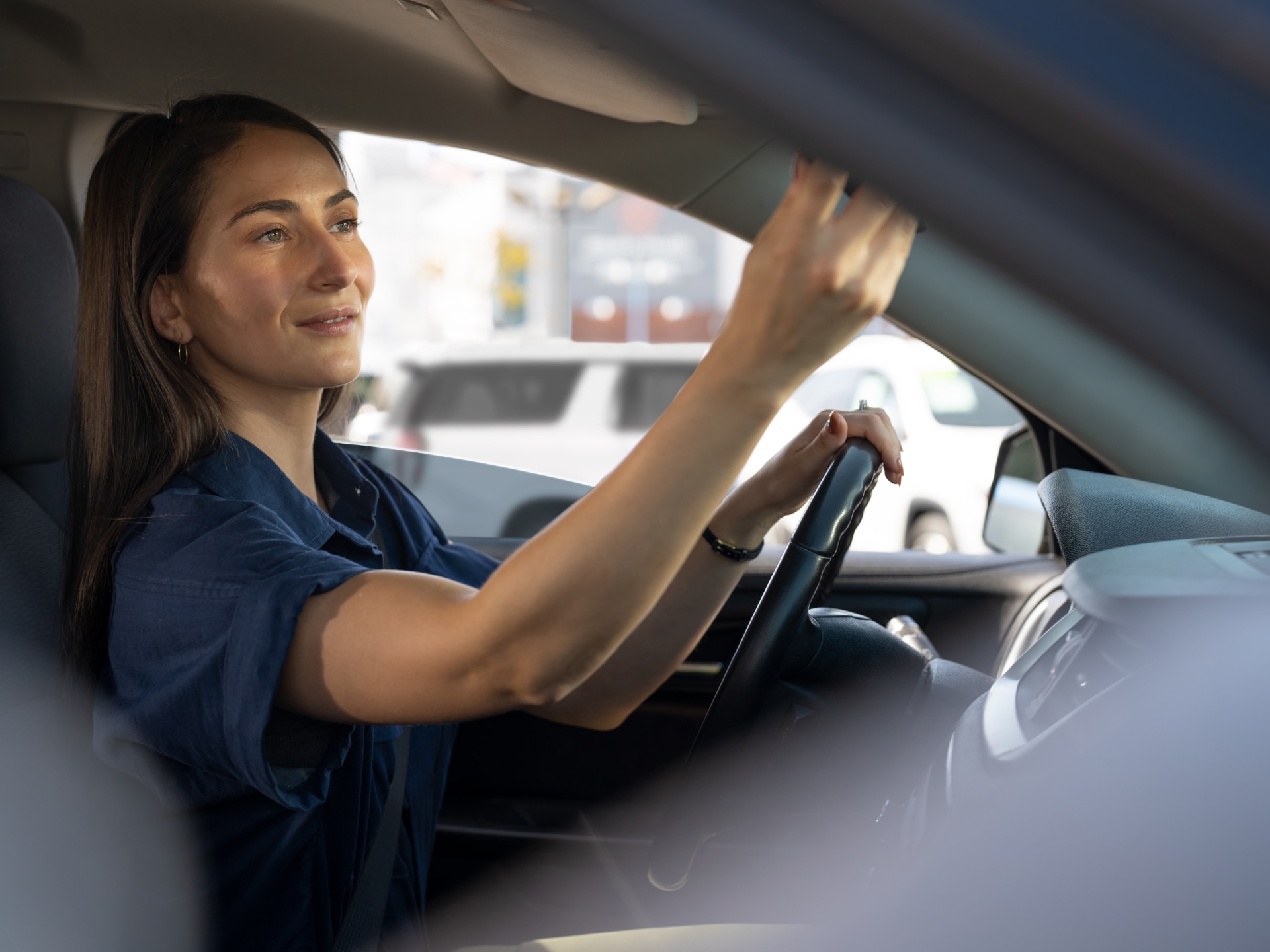 A Woman Adjusting the Sun Visor While Sitting in the Driver's Seat of a Vehicle