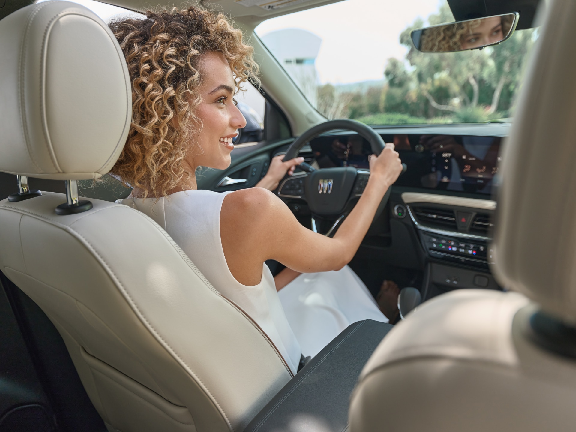 A Woman Smiling in the Drivers Seat of a Buick Encore GX as she Looks Over at the Passenger Seat