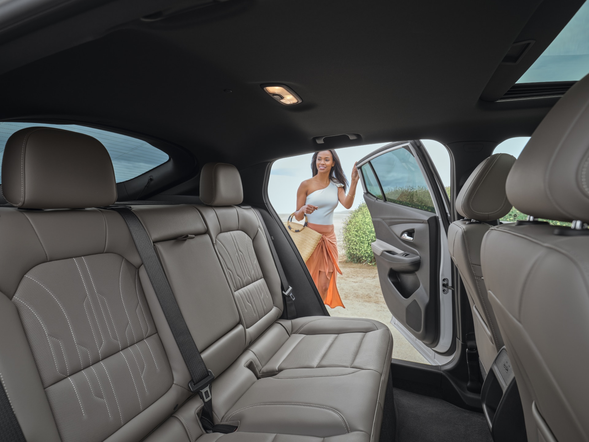 View From the Interior Rear Seats of the Buick Envista as a Woman Opens the Rear Drivers Side Door