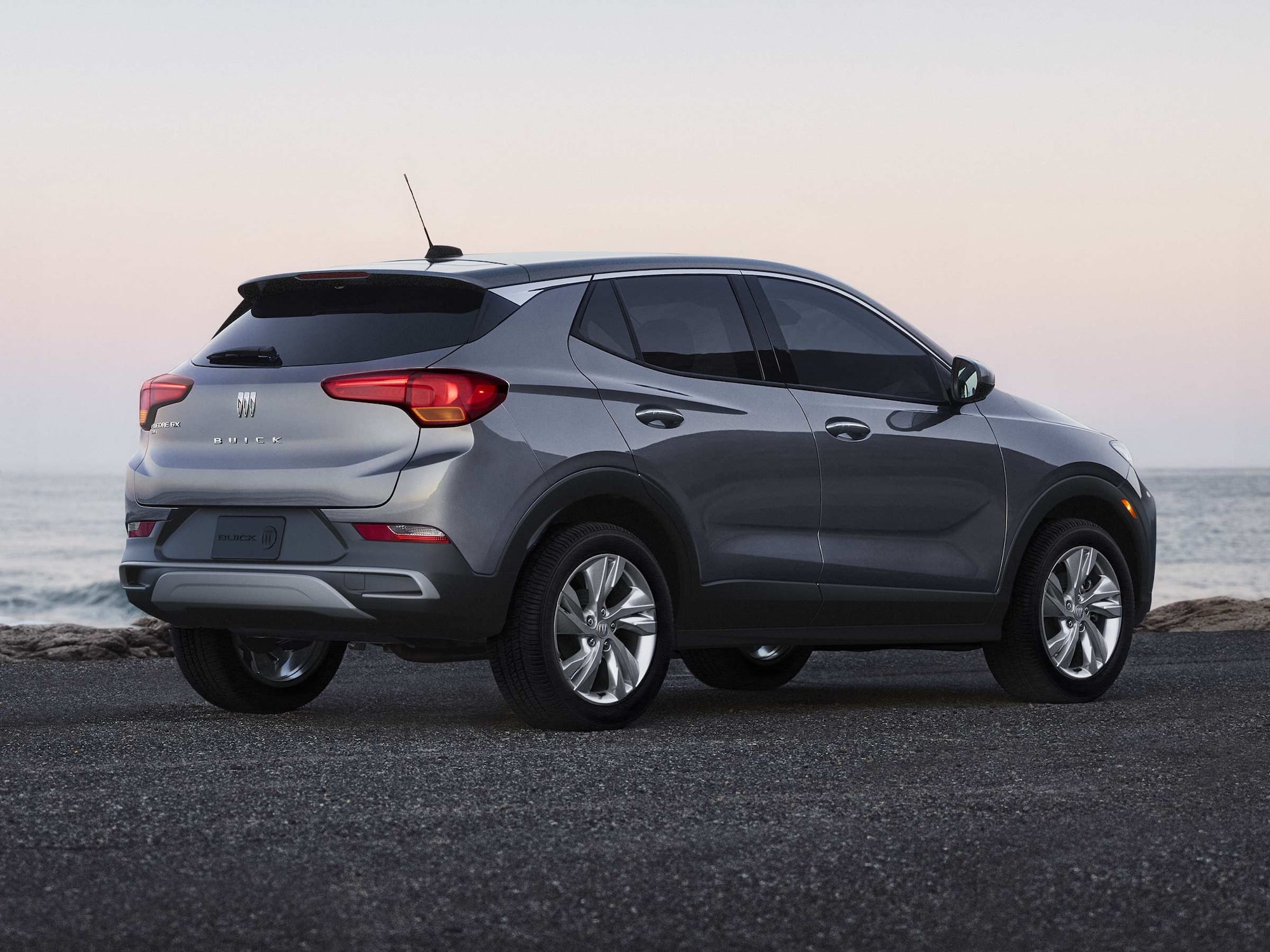 ] A Gray Buick Encore GX SUV Parked on Pavement Overlooking a Body of Water