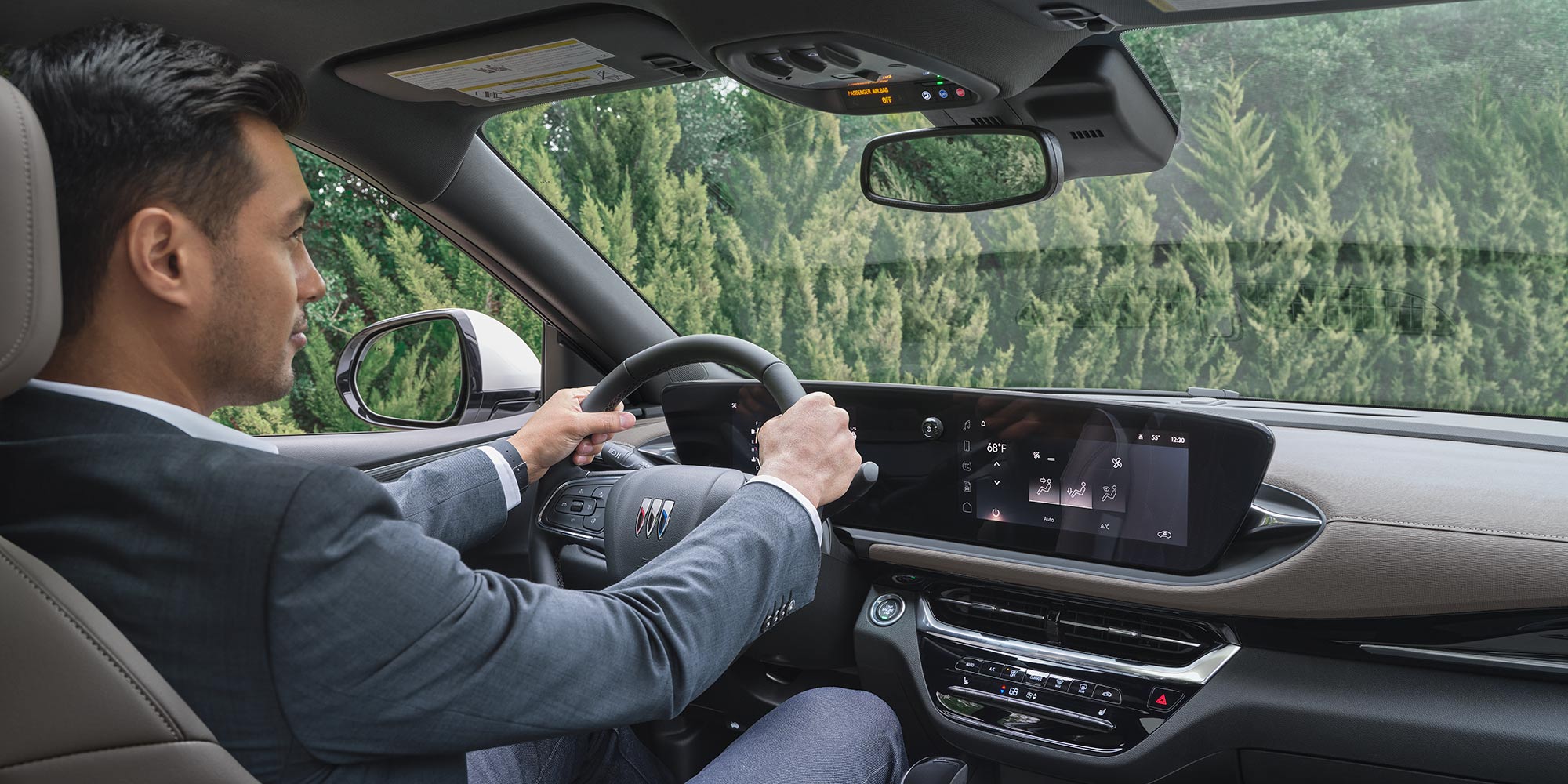  A Man Driving a Buick Envista with His Hands on the Steering Wheel and a Panoramic Sunroof Above