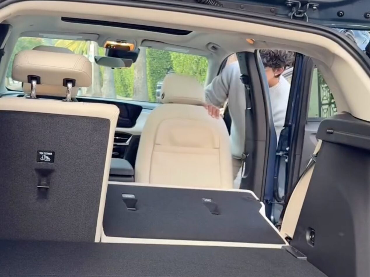 An Interior View Looking Into the Cargo Area of a Buick SUV With Light Colored Seats Folded Down and a Person Entering the Passenger Side