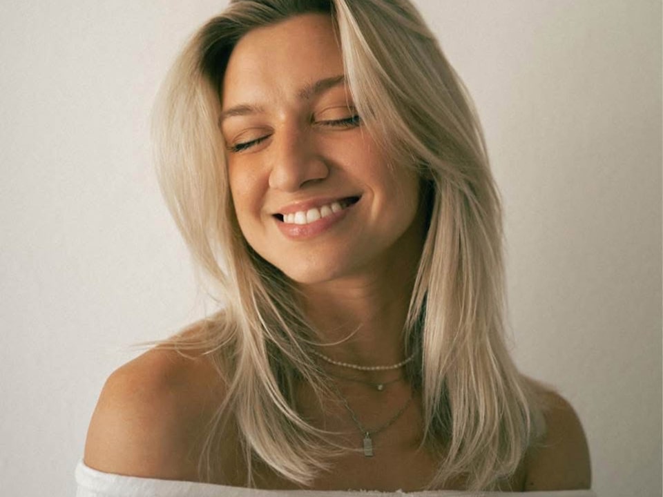Anna Sitar Smiling With Closed Eyes And a White Off-The-Shoulder Top