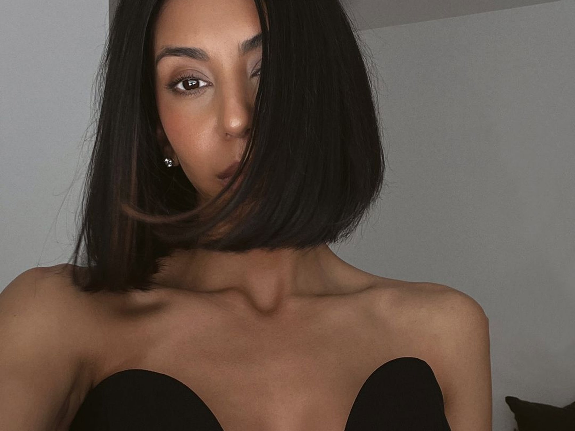 Kayla Seah With Short Dark Hair Wearing a Strapless Black Top Looking At The Camera