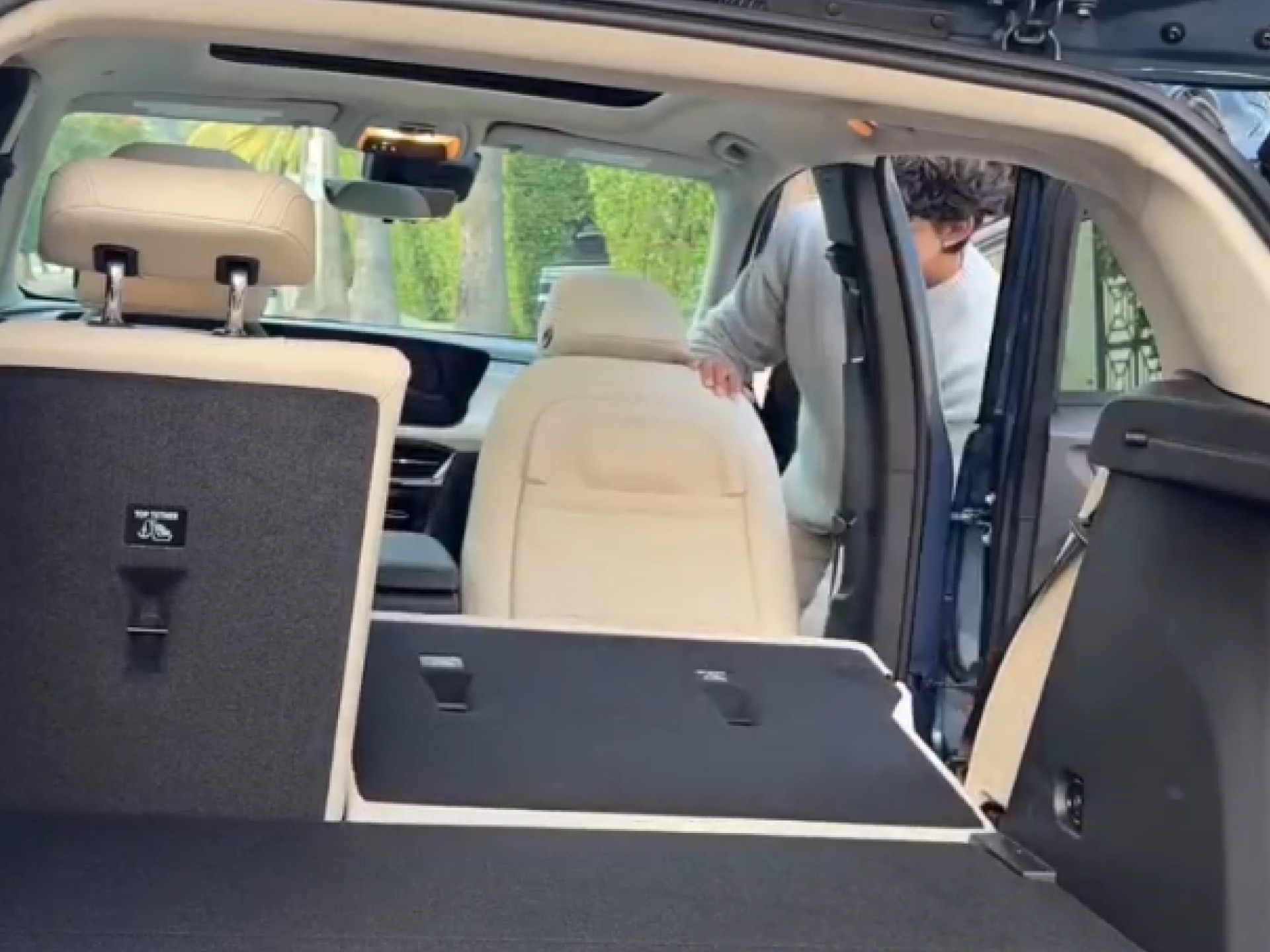 An Interior View Looking into the Cargo Area of a Buick SUV with Light Colored Seats Folded Down and Marco Zamora Entering the Passenger Side