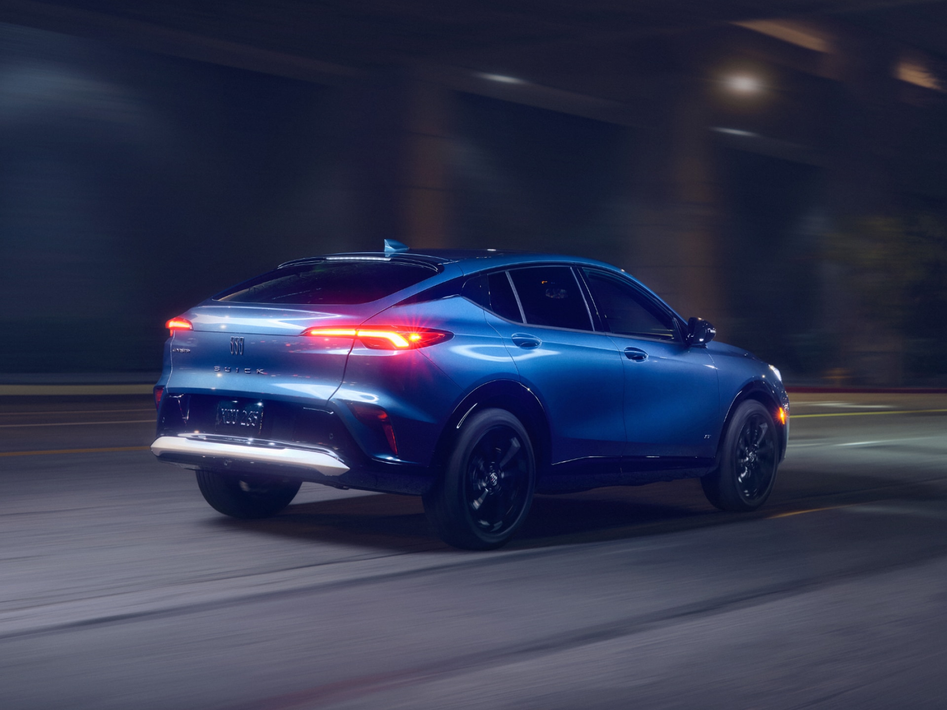 A Rear Three-Quarters View of a Blue Buick Envista ST Driving at Night Along a Lit City Street