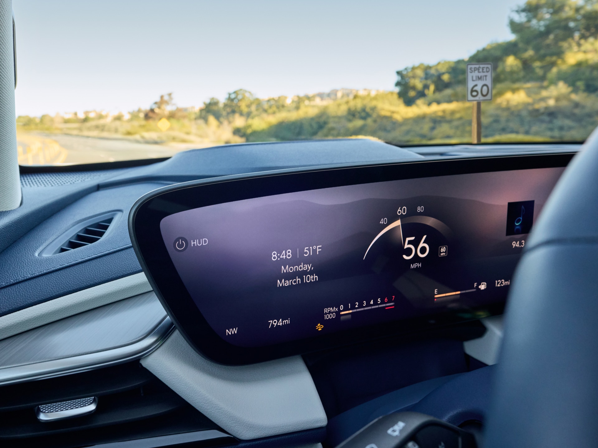 A Buick Dashboard's Curved Digital Screen Displays Speed and Driving Data While a Speed Limit Sign is Visible Through the Windshield