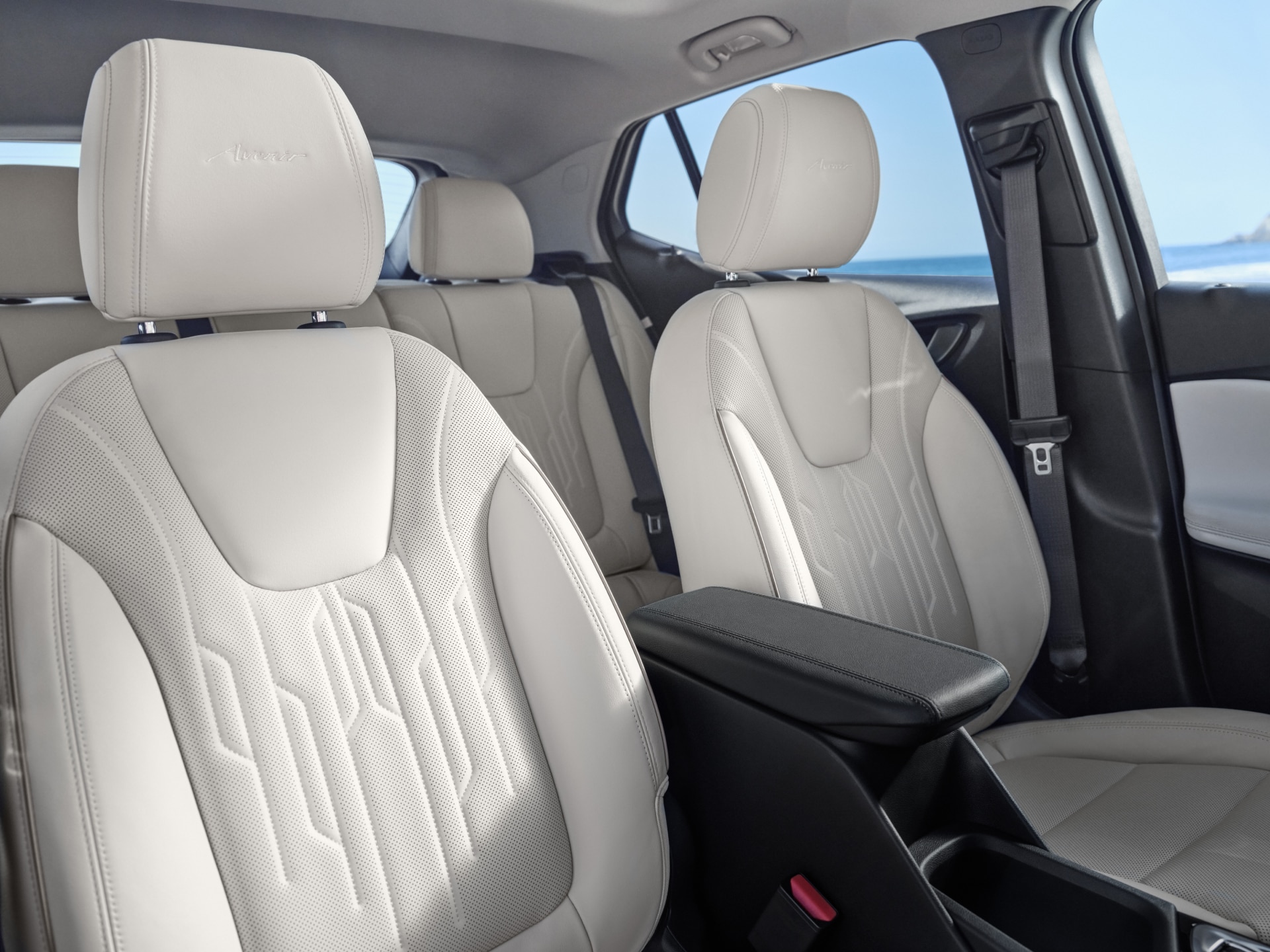 An Interior View of a Buick Avenir with White Leather Front and Rear Seats and an Armrest with the Ocean Visible Outside. 