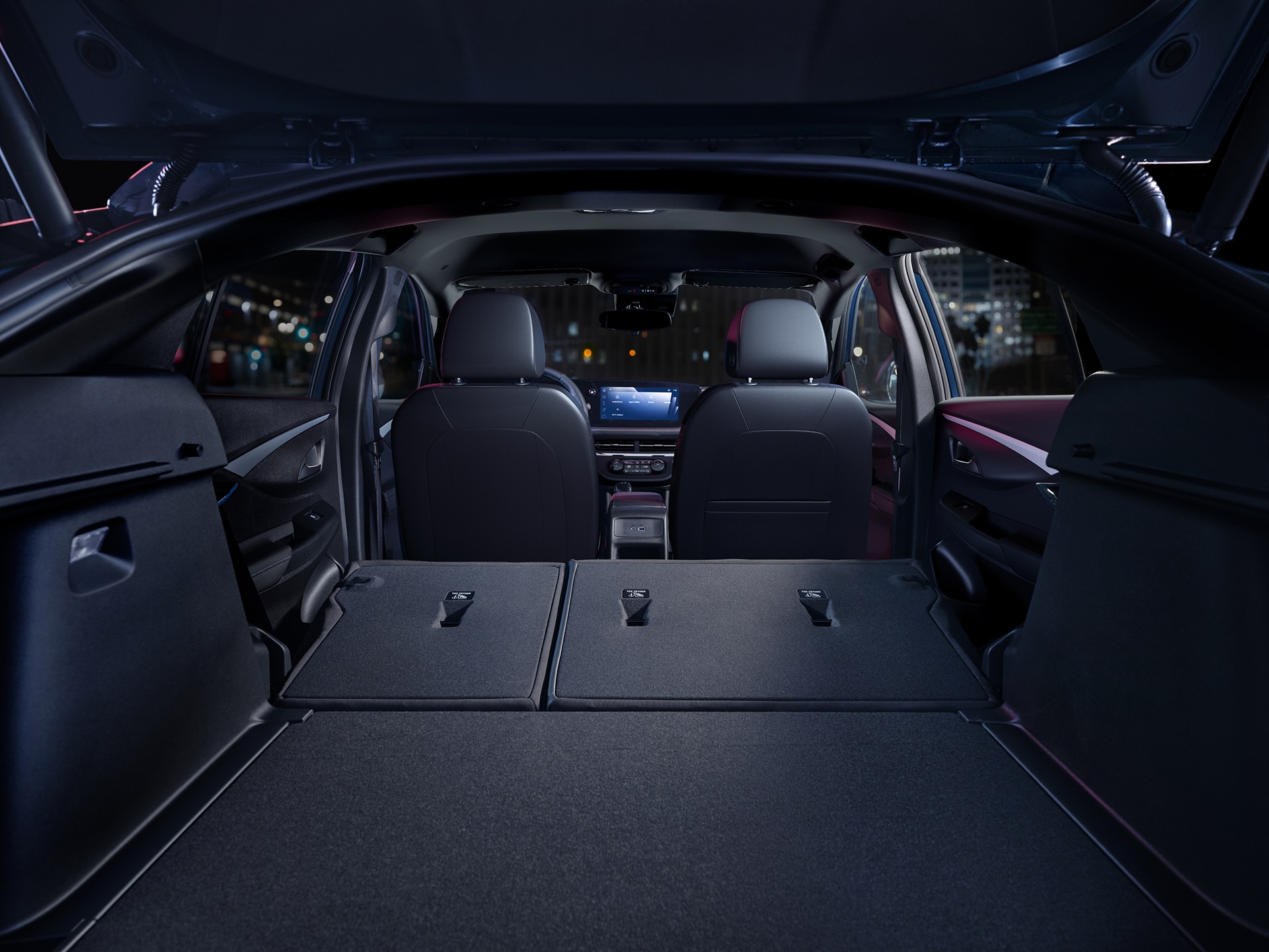 The rear interior of a 2026 Buick Envista with seats folded down at night in a city.