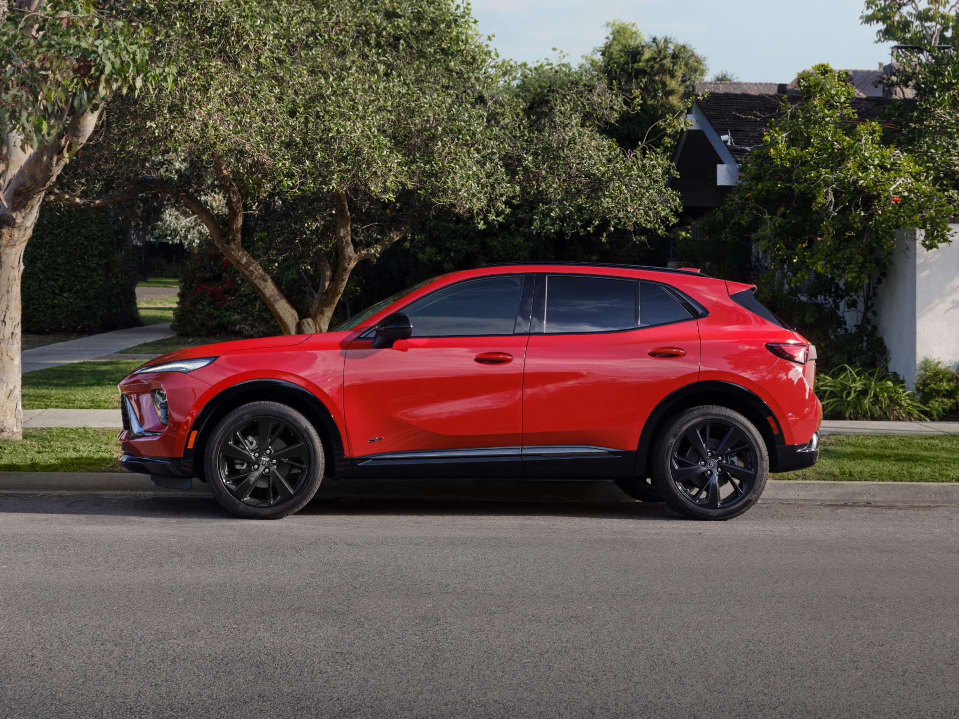 A Red Buick Encore GX ST Parked on the Side of a Street with Trees in the Background