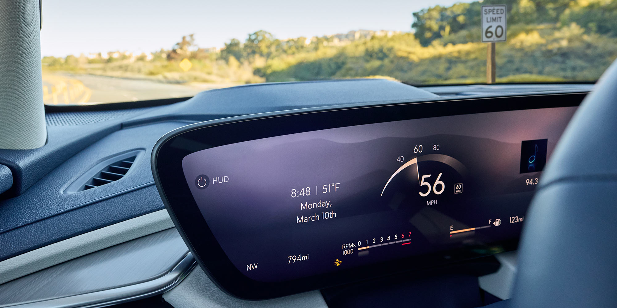 A Buick Dashboard's Curved Digital Screen Displays Speed and Driving Data While a Speed Limit Sign Is Visible through the Windshield