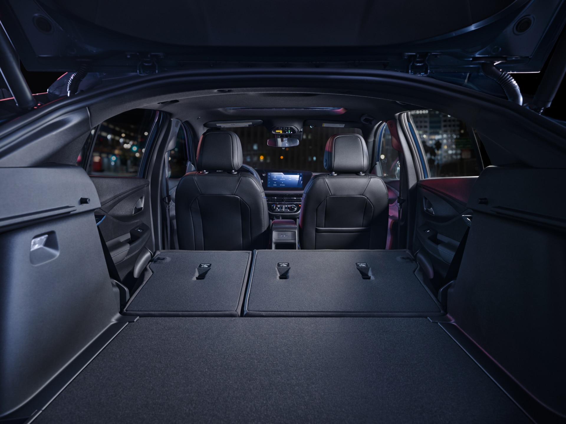 The Open Trunk of a Buick Vehicle with Rear Seats Folded Down Revealing Spacious Cargo Area at Night