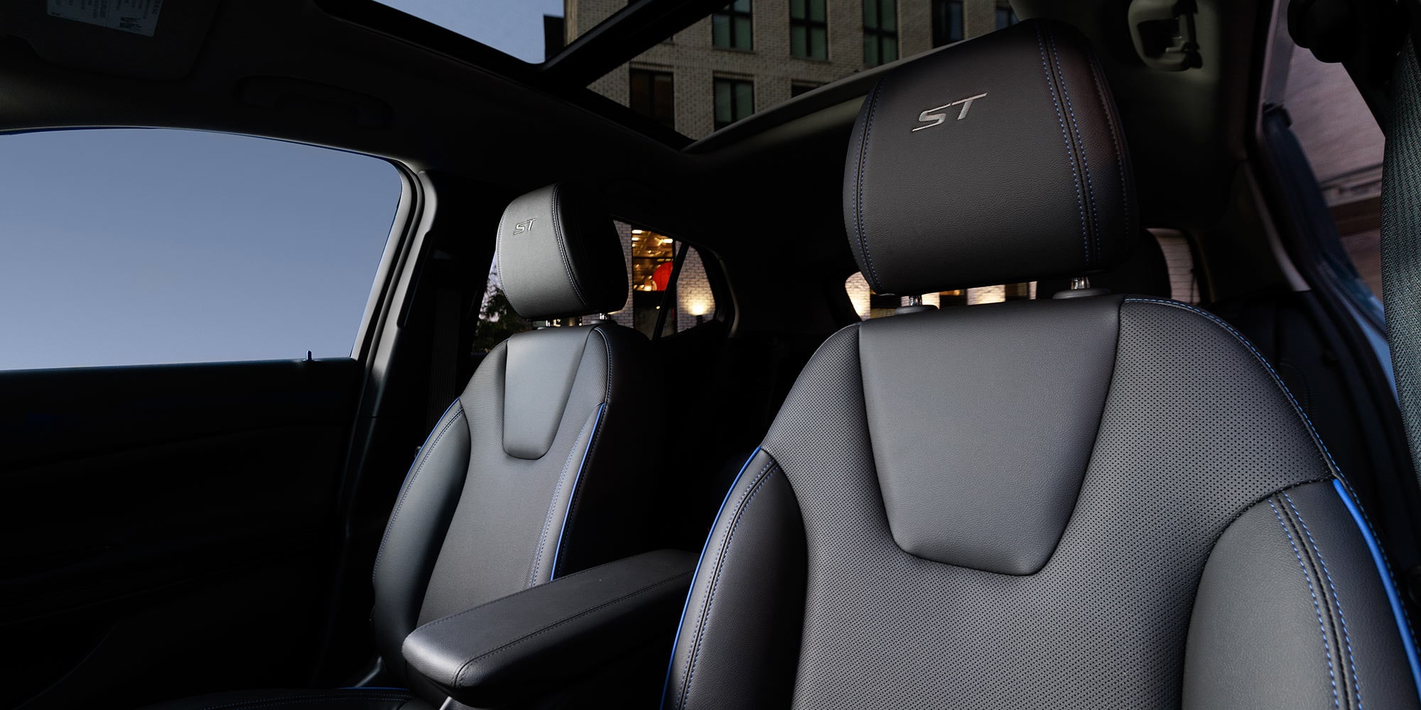 Interior View of a Car Featuring Black Leather Seats with Blue Stitching a Panoramic Sunroof and an ST Logo on the Headrest