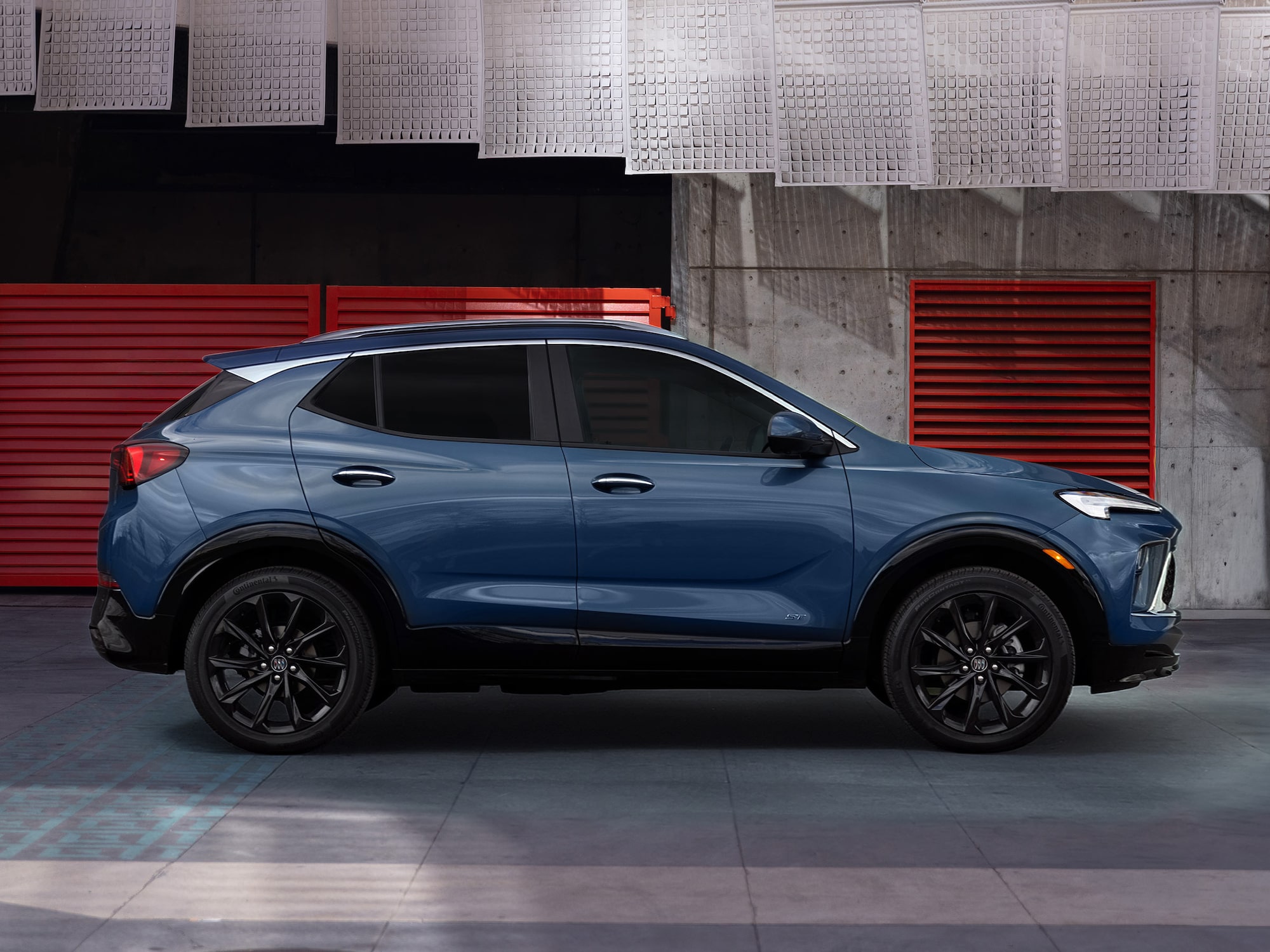 A Deep Blue Buick Crossover SUV with Black Wheels and Trim Parked in a Garage with Red Doors