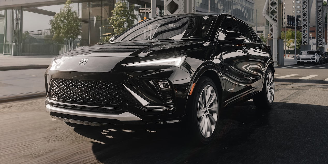 A Sleek Black Buick SUV Driving on a City Street with Modern Buildings and a Bridge