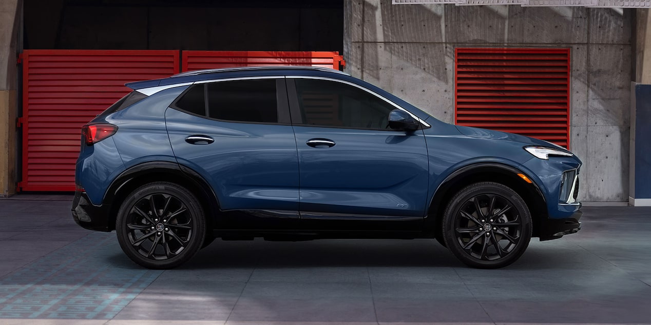 A Deep Blue Buick Crossover SUV with Black Wheels and Trim Parked in a Garage with Red Doors