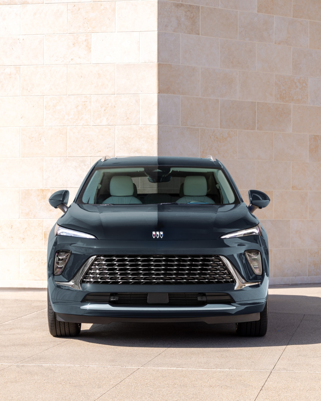 A Front View of a Buick Luxury SUV Parked in Front of a Marble Building on a Sunny Day.
