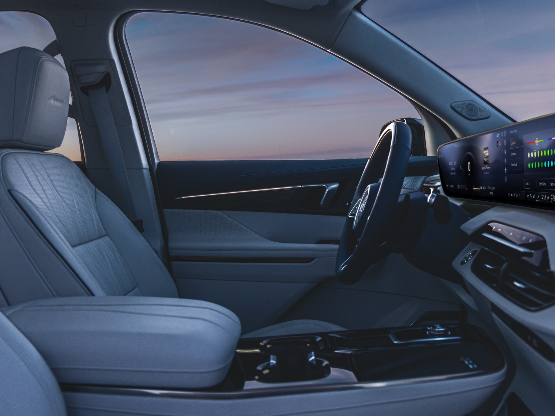 A Buick Vehicle’s Driver’s Seat, Steering Wheel, and Center Console Shown From the Passenger’s Seat, at Sunset