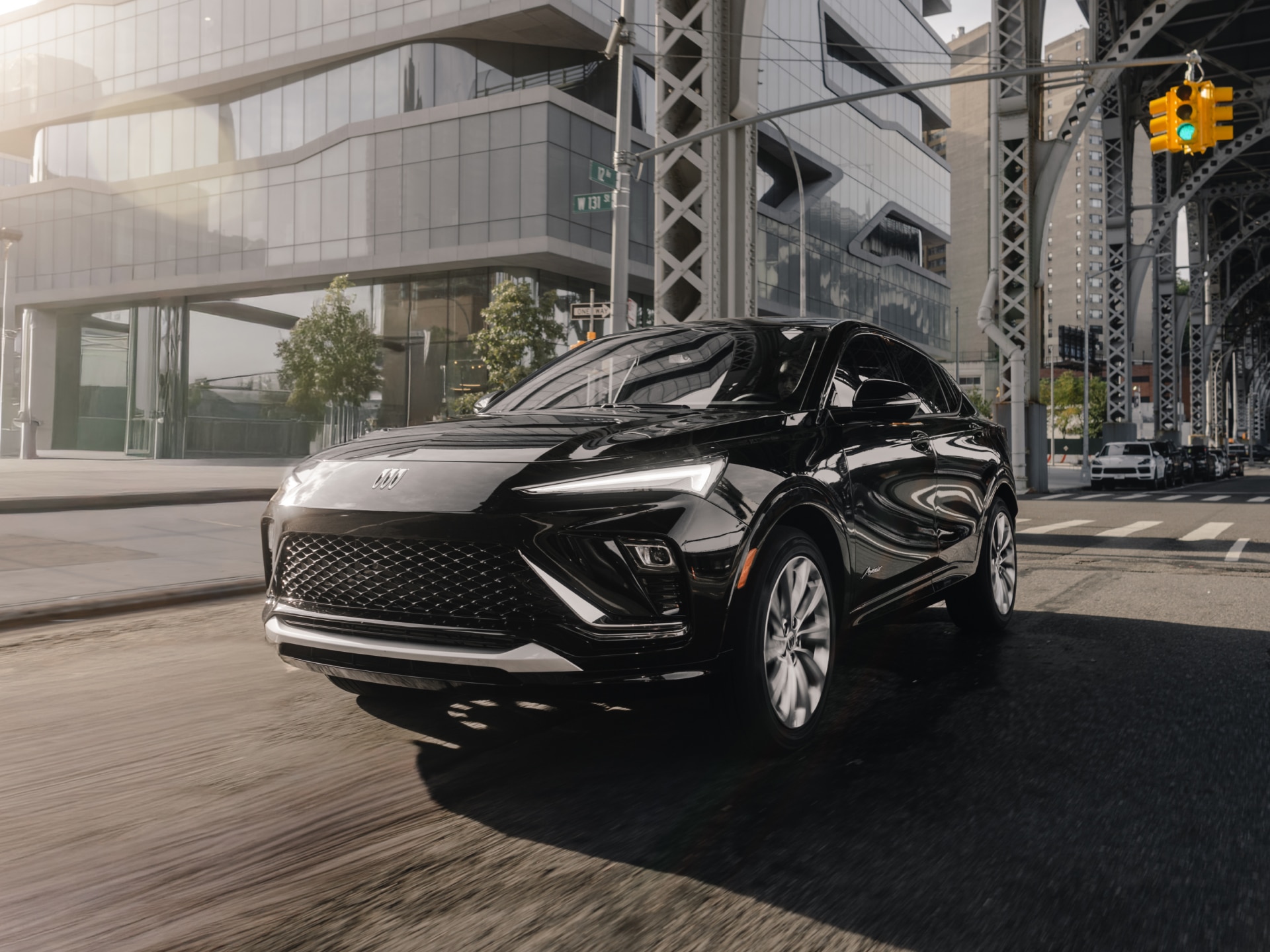 A Sleek Black Buick SUV Driving on a City Street with Modern Buildings and a Bridge