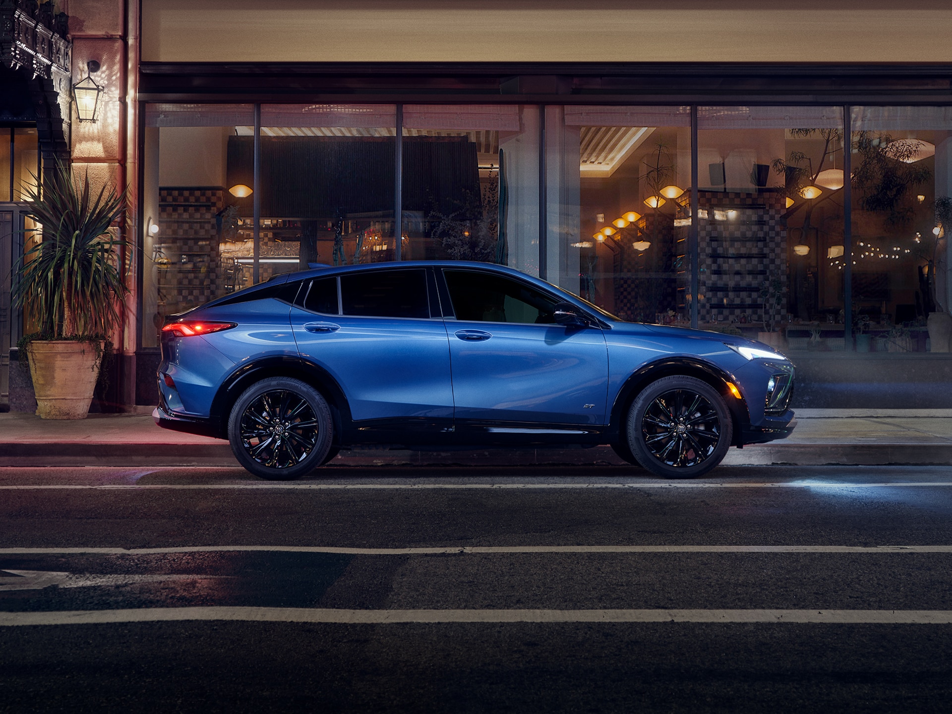 Profile View of a Blue Buick Envista Compact Crossover Parked at Night on a City Street