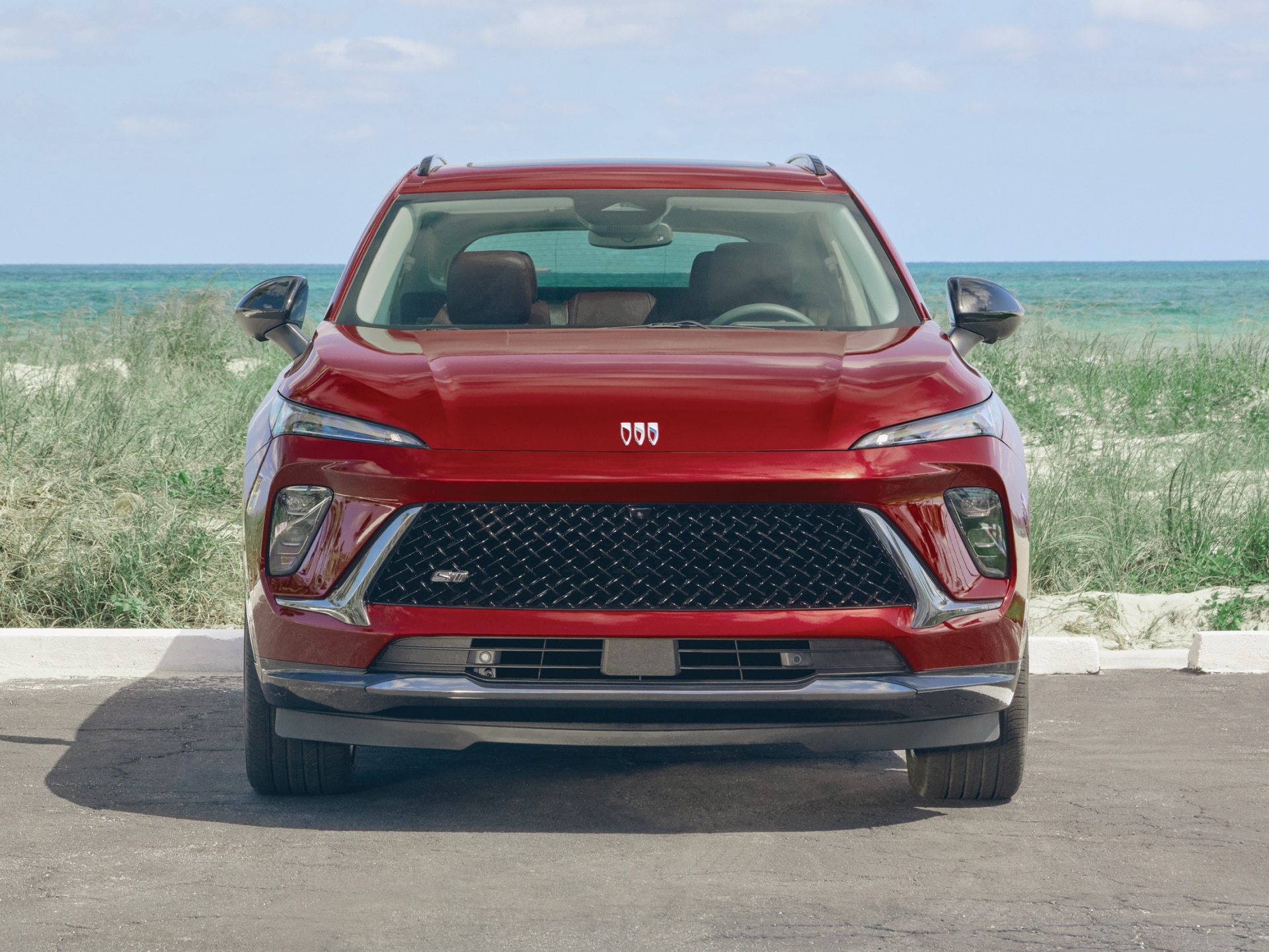 Front View of a Red Envision Sport Touring Parked in Front of a Body of Water