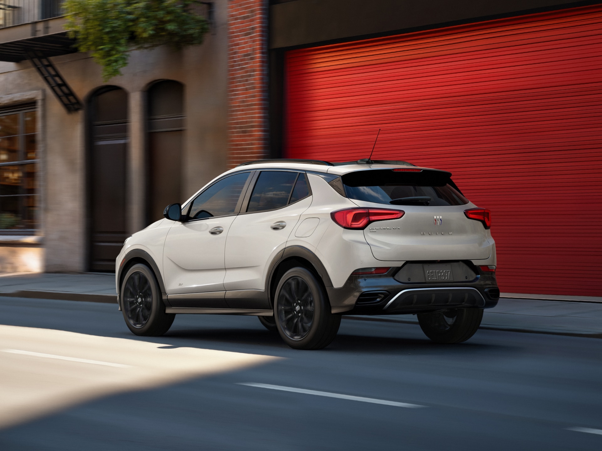 The 2026 Buick Encore GX Sports Touring SUV in the Color Ceramic Driving Down a City Street