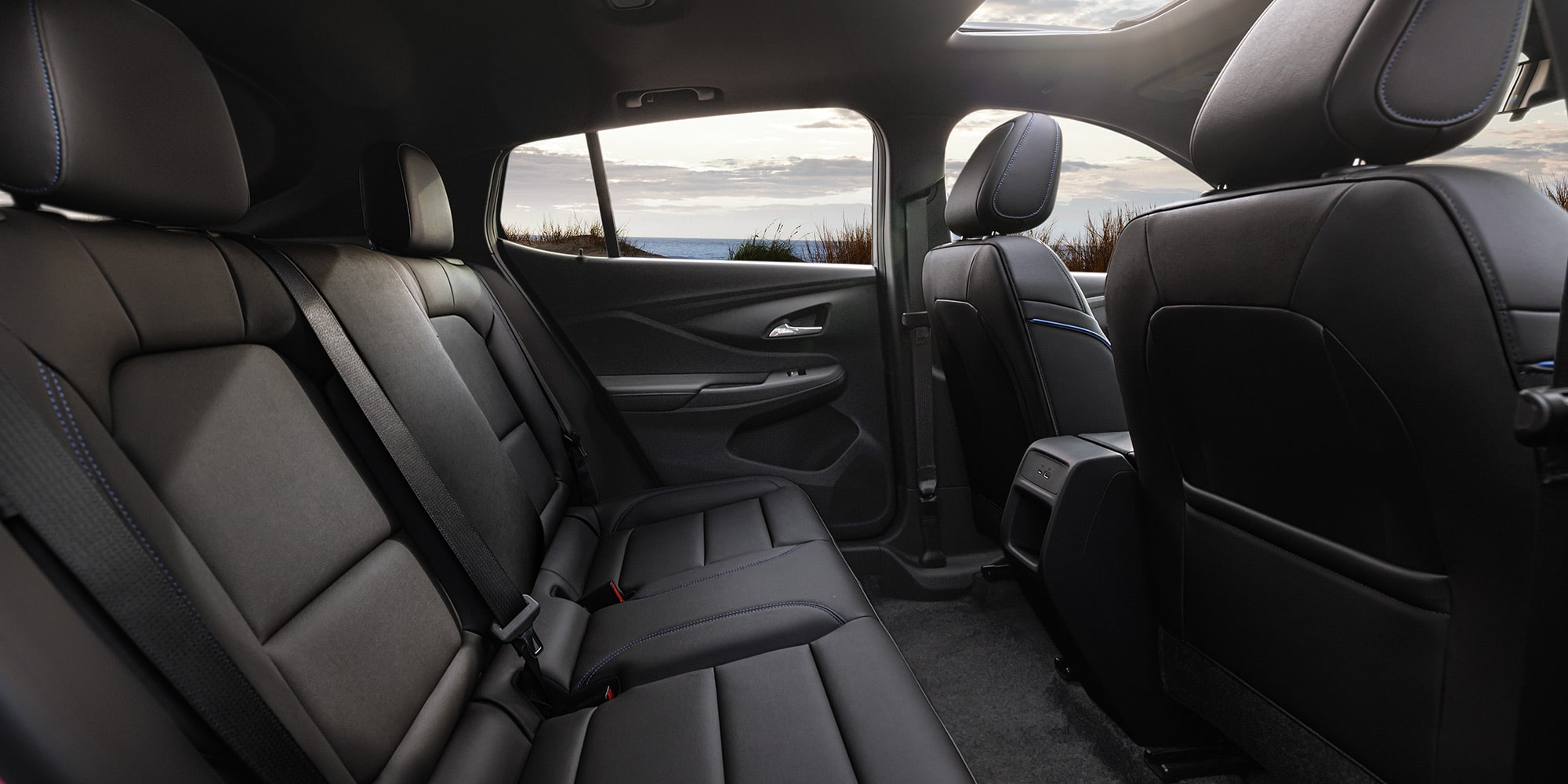 The Interior of a Buick Features Black Leather Seats a Sunroof and the Ocean Visible Through the Windows