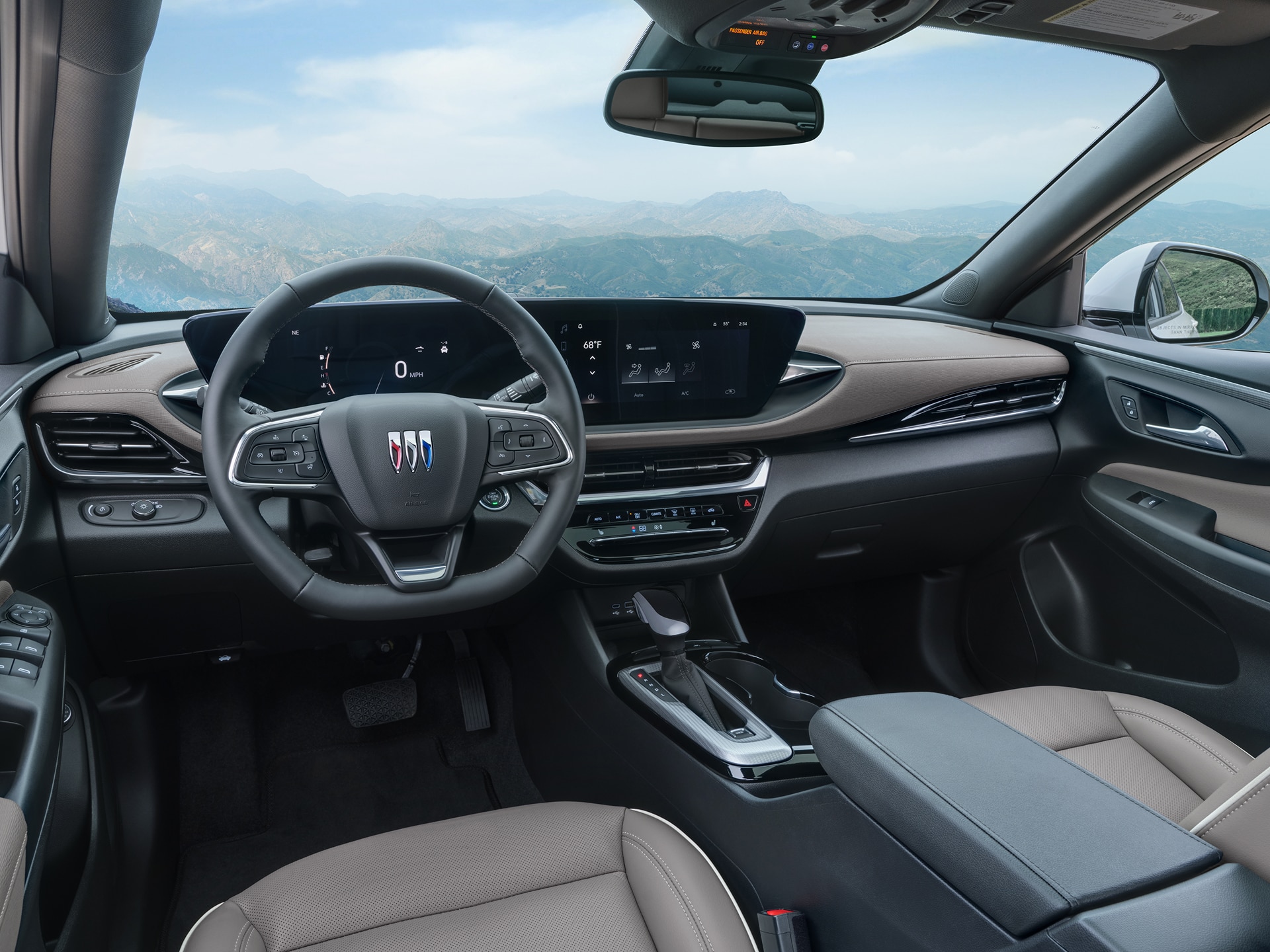 The Modern Interior of a Buick SUV Features a Digital Dashboard, Steering Wheel with Buick Logo, and Mountain Scenery Outside