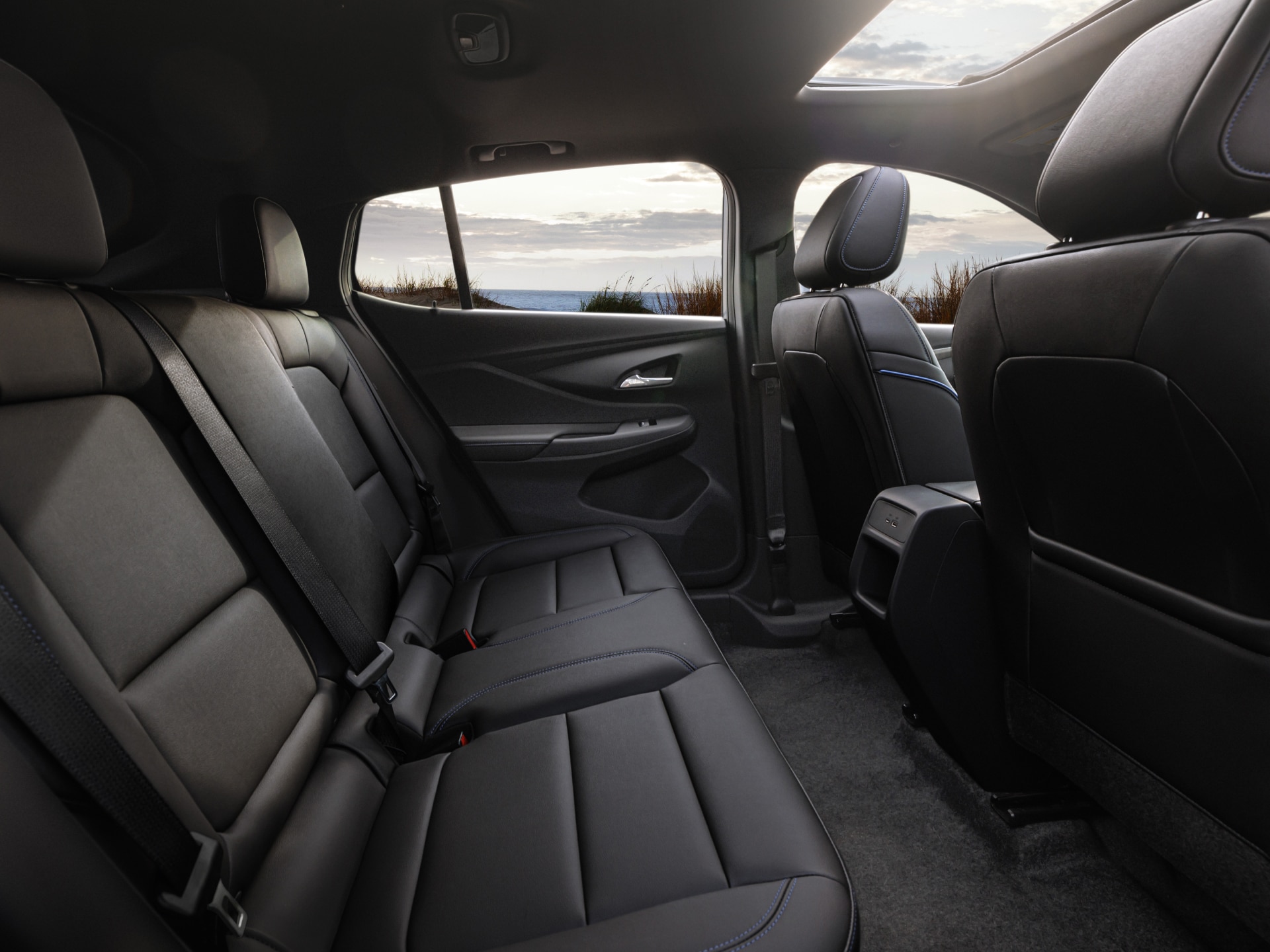 The Interior of a Buick Features Black Leather Seats a Sunroof and the Ocean Visible Through the Windows