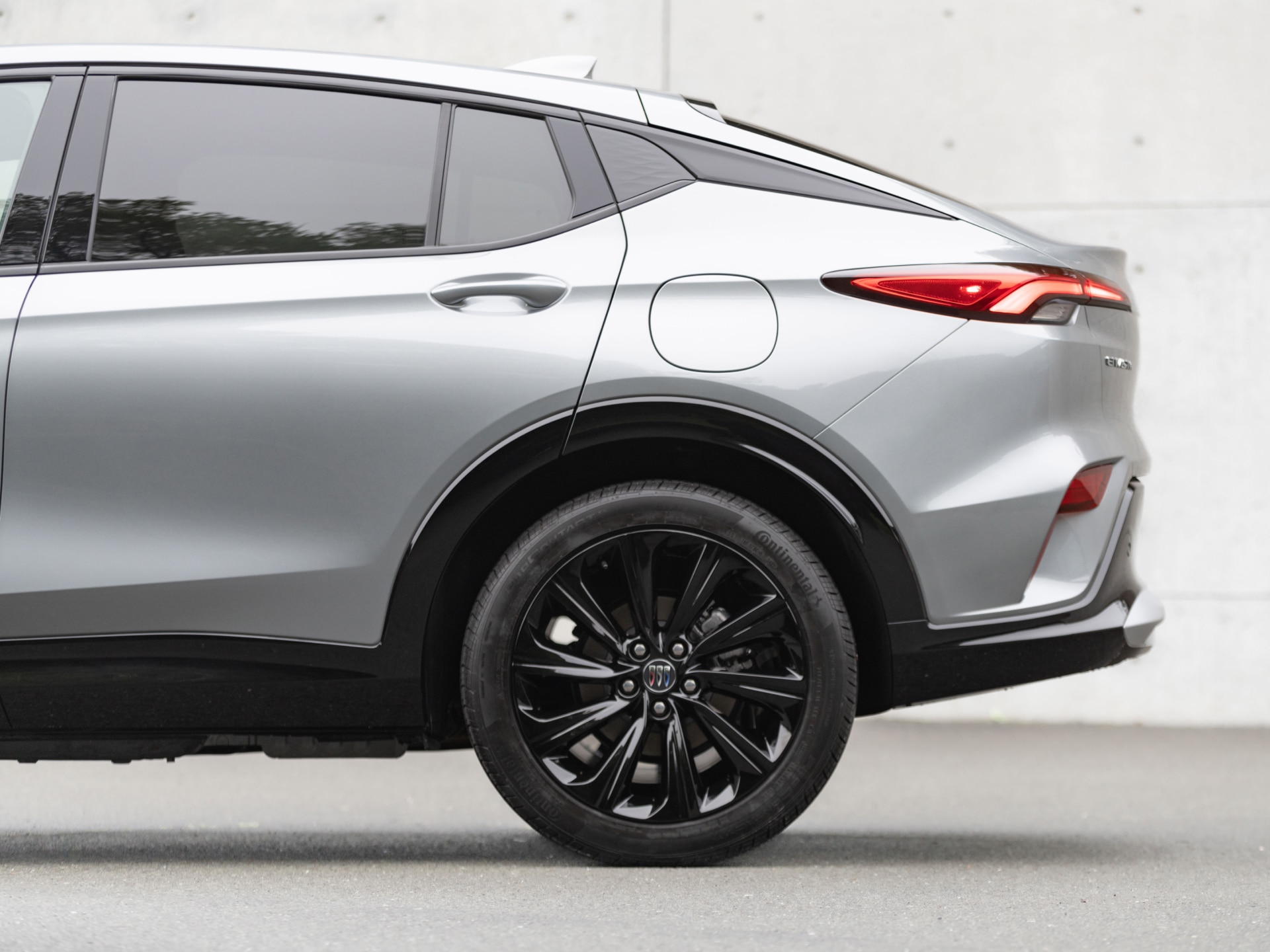 A Close-Up Side View of a Silver Buick SUV's Rear Wheel, Taillight, and Fuel Cap
