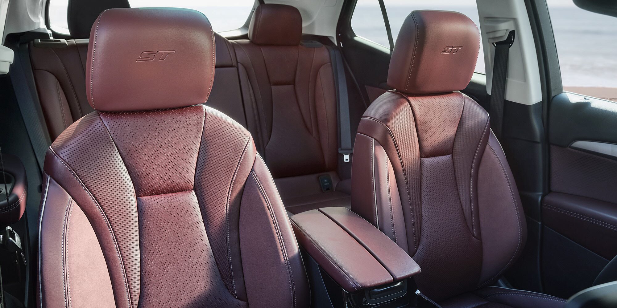 Interior View of a Buick Car with Perforated Dark Red Leather Seats, an ST Logo Embroidered on the Headrests, and a Center Console with Cup Holders