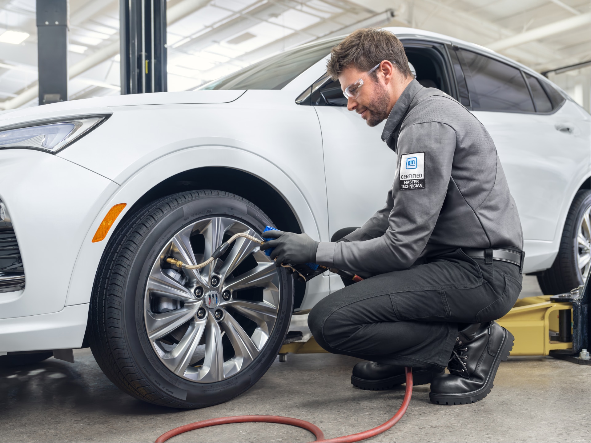 A Buick Certified Master Technician Checks the Tire Pressure on a White Buick SUV Wheel