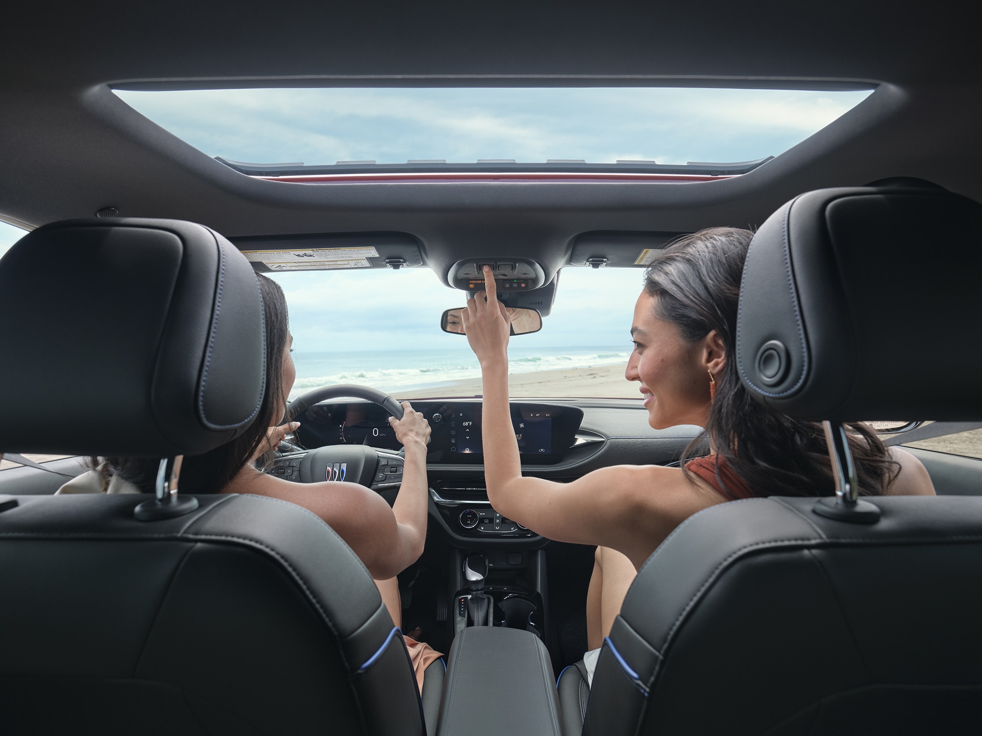 Two Young Women Are Inside a Buick SUV Looking out at a Beach and the Ocean
