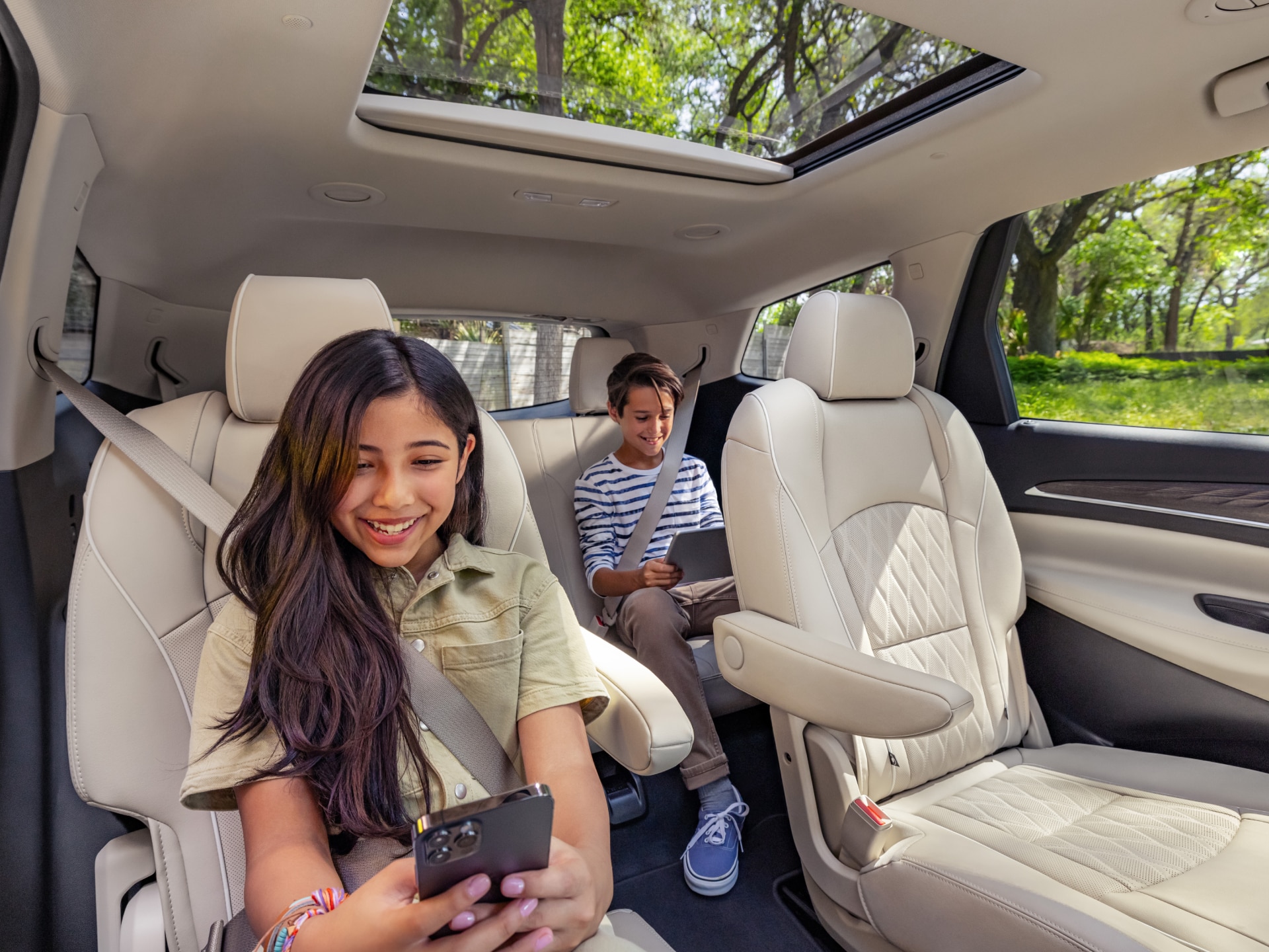Young Kids Sitting in the Back Seat of the Vehicle Using an iPad and a Smartphone