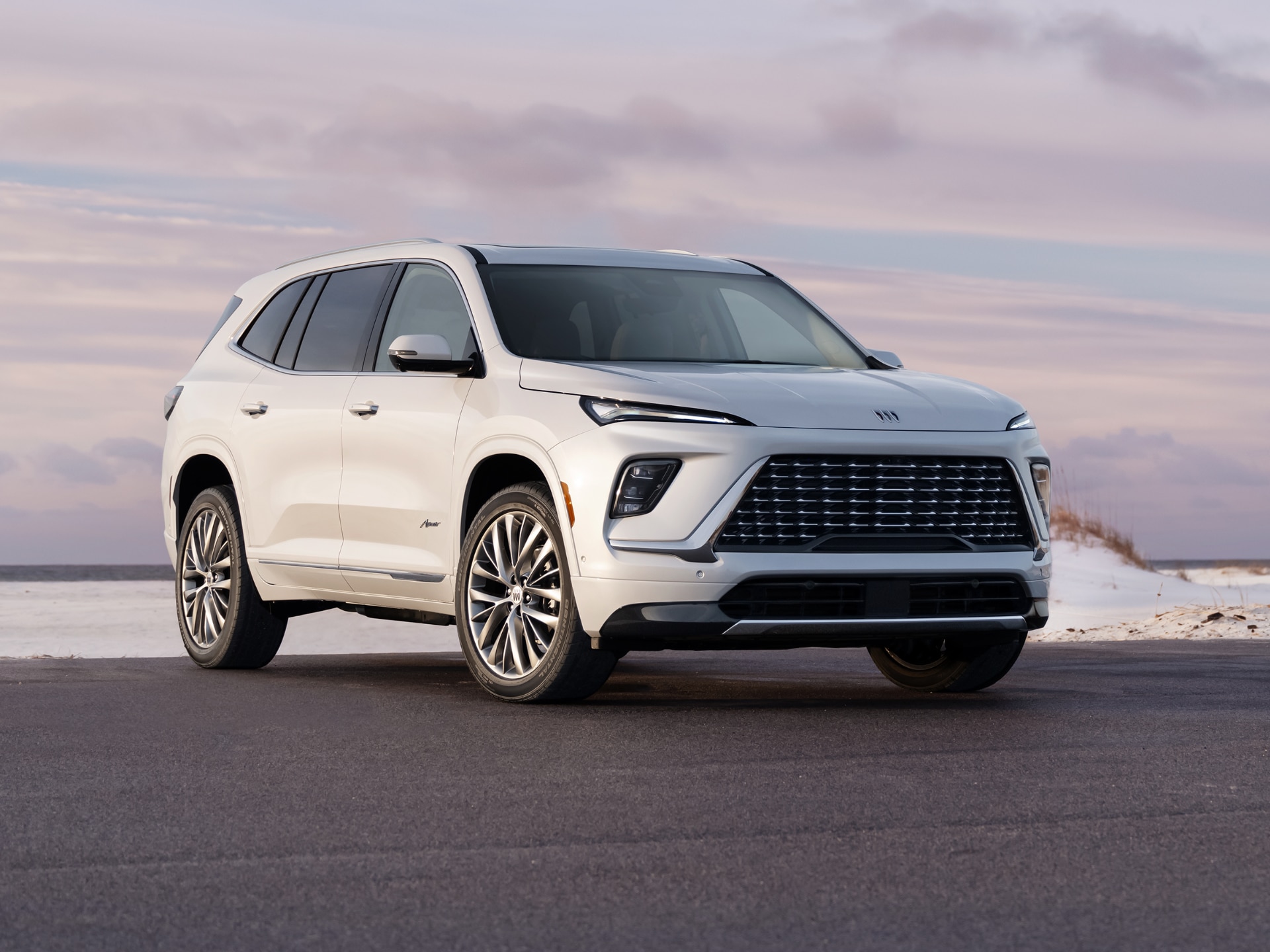 A White Buick Enclave SUV Parked on an Asphalt Road near a SandyBeach during Sunset