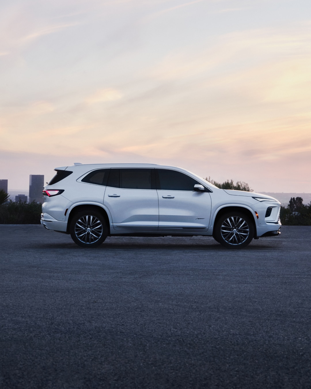 Profile View of a White Buick SUV with a City Landscape in the Distance