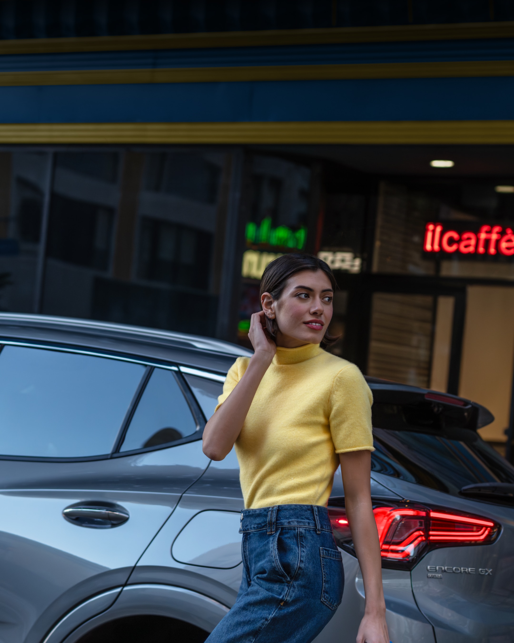 A Woman Standing by a Gray Buick SUV on a City Street