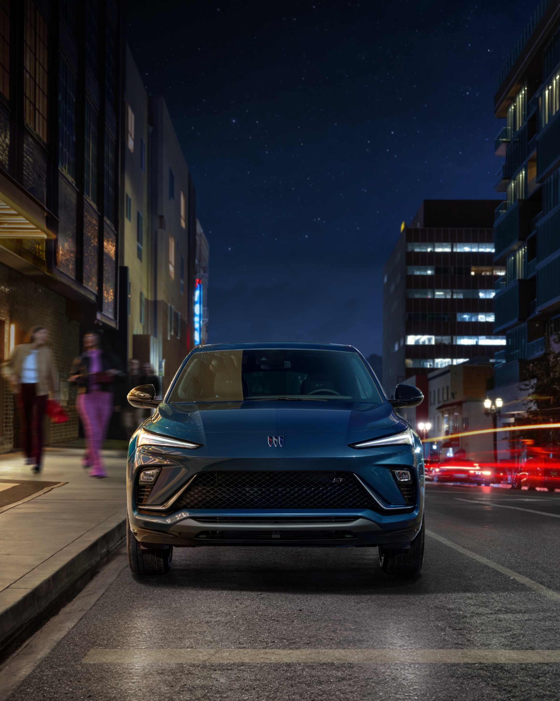 A Blue Buick Envista SUV Driving on a City Street at Night