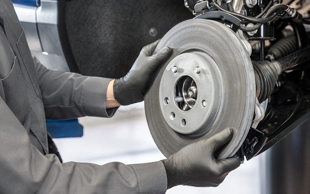 A Mechanic with Gloves Putting in a Wheel In a Vehicle