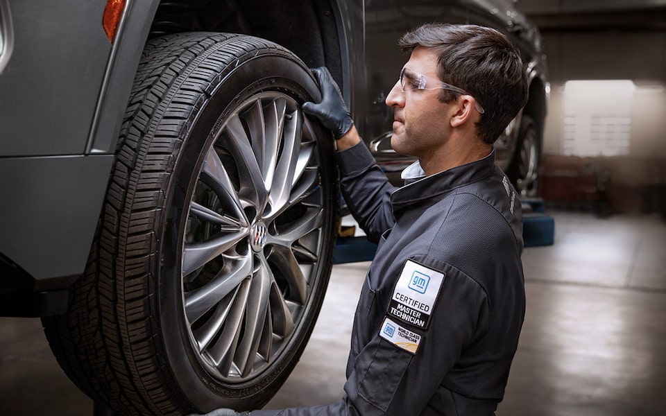 A Male Service Tech Installing a Tire on a Raised Vehicle